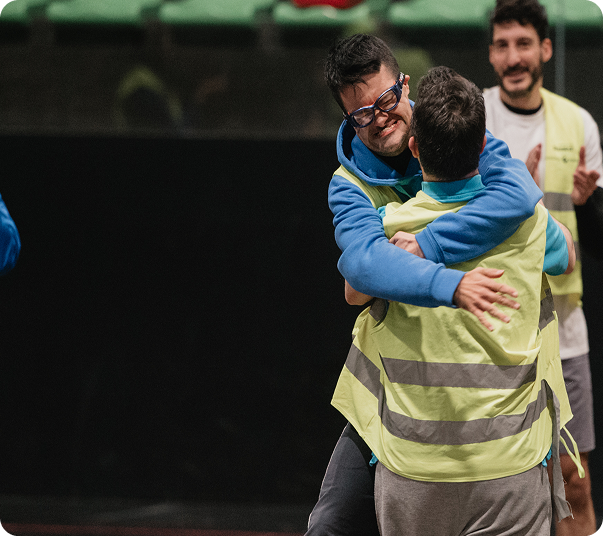 Dos personas se abrazan mientras un voluntario aplaude