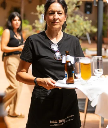 Camarera posa a cámara sosteniendo una bandeja con una copa de cerveza